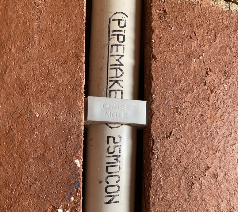 A ChaseMate plug holding 25mm pipe firmly inside a brick chase