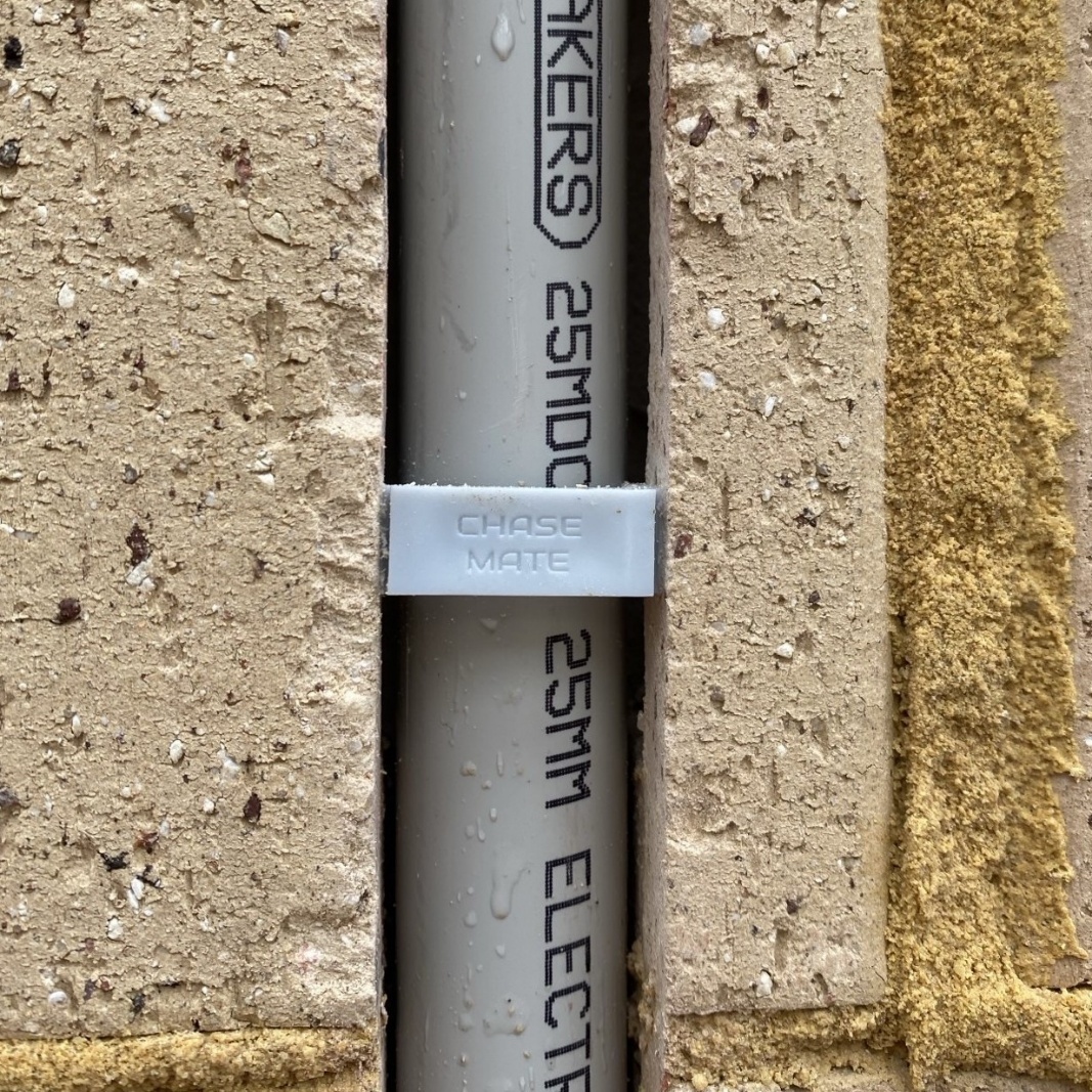 Conduit held flush in a brick chase by a ChaseMate plug