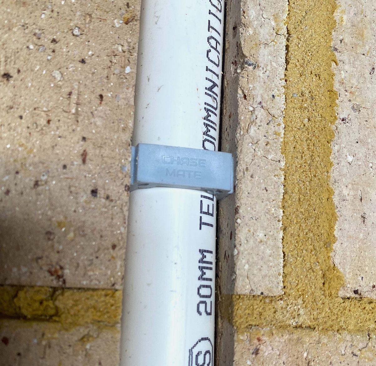 ChaseMate retaining plug holding a utility line inside a chased brick wall channel